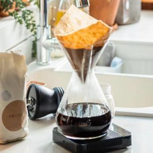 Coffee being filtered into a chemex on a kitchen counter.